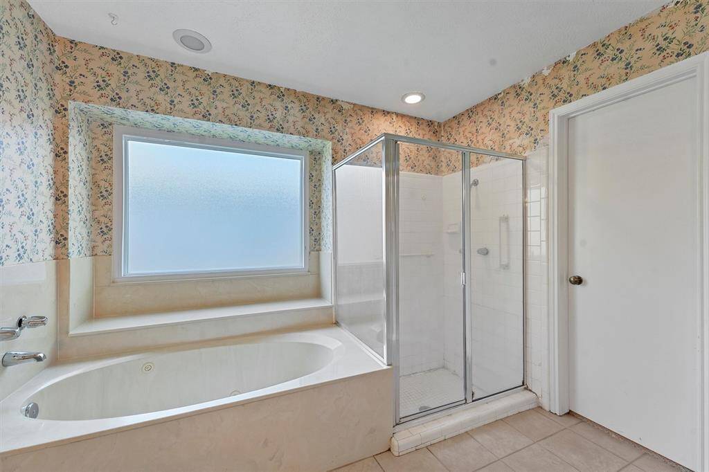 The bathroom features a large soaking tub beneath a frosted window and a separate glass-enclosed shower.
