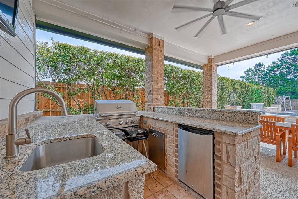 Outdoor kitchen equipped with sink, dishwasher and grille.