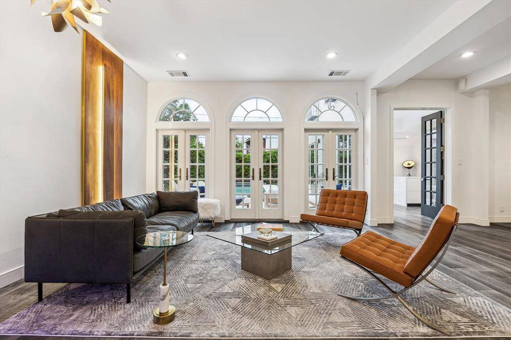 Sophisticated study exuding timeless elegance, with crisp white paneling and coffered ceilings that add architectural depth. Built-in shelving and a wood burning fireplace enhance both function and charm.