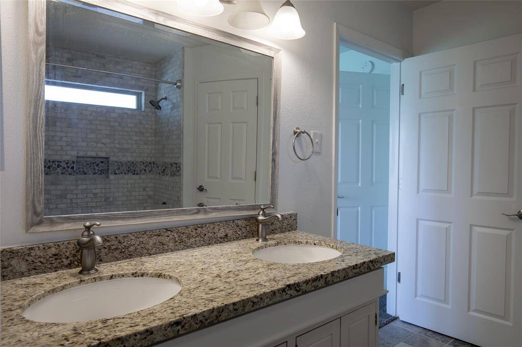 Primary bathroom enjoys double sinks with granite and all of the latest touches