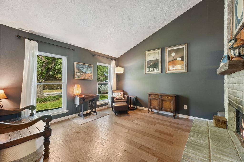 Another view of the striking two-story brick fireplace, a true focal point of the home. The metal railing above adds a modern touch and offers a clear view into the upstairs game room, creating an open and connected feel throughout the space.