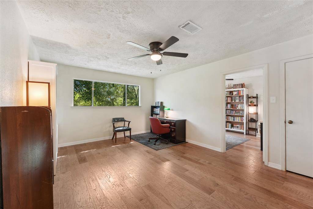 Dining room with a wood accent wall and a brick view of the striking two-story fireplace that separates it from the living room. Warm and inviting for any occasion.