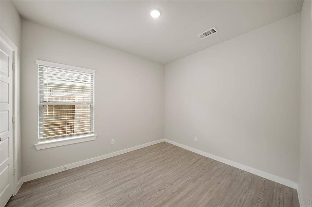 Secondary bedroom with vinyl floors, a built-in closet, and a window with privacy blinds.