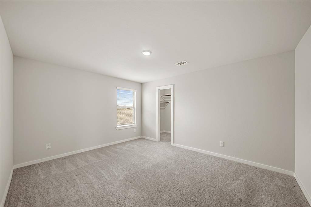 Secondary bedroom with carpet floors, a built-in closet, and a window with privacy blinds.