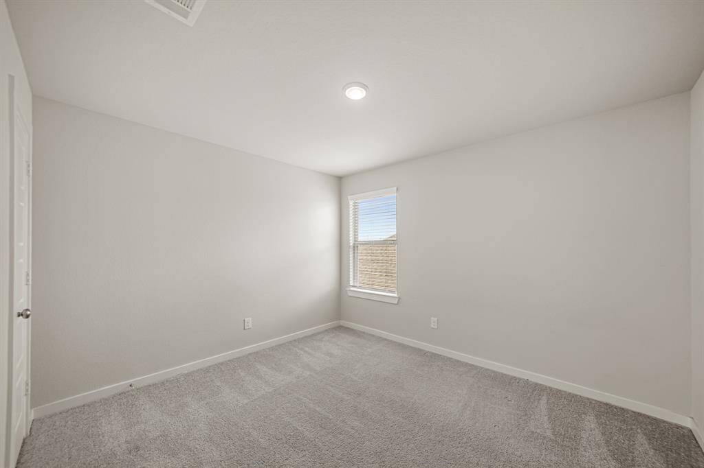 Secondary bedroom with carpet floors, a built-in closet, and a window with privacy blinds.