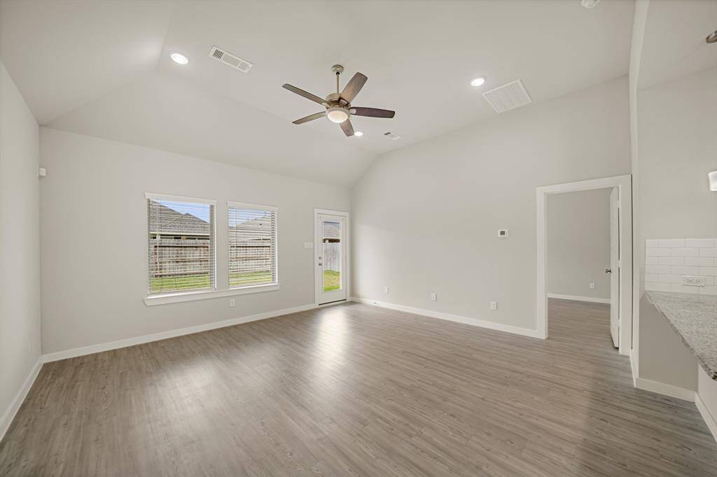 Check out this open and bright living room, it has a high ceiling with a ceiling fan, recessed ligting, windows with privacy blinds, and great views into your backyard.