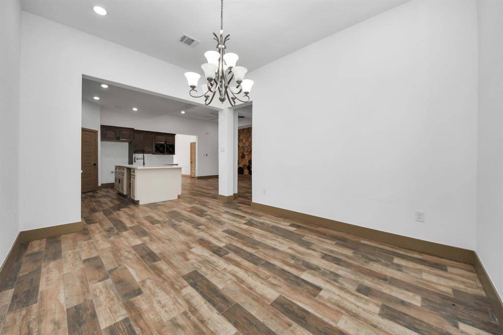 spacious, open-concept dining area , a modern chandelier, and a view of a kitchen