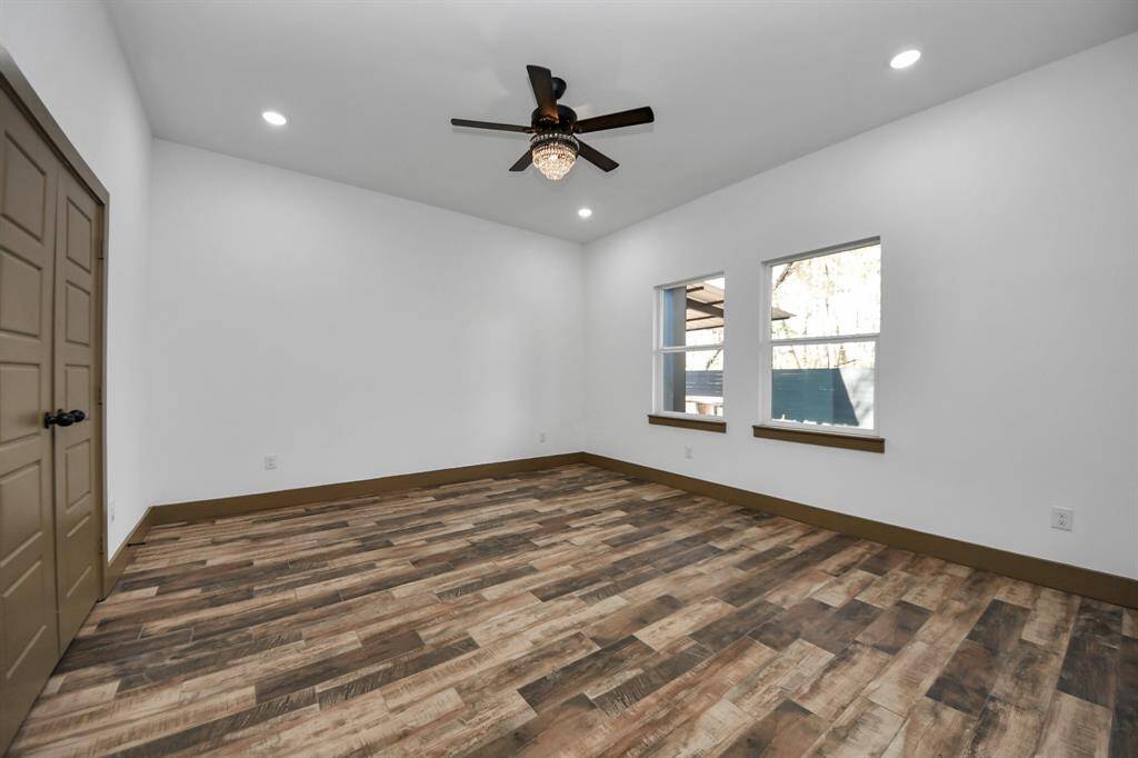 Primary room features wood-style flooring, neutral walls, and a modern ceiling fan. It includes a double-door entryway leading to a bathroom