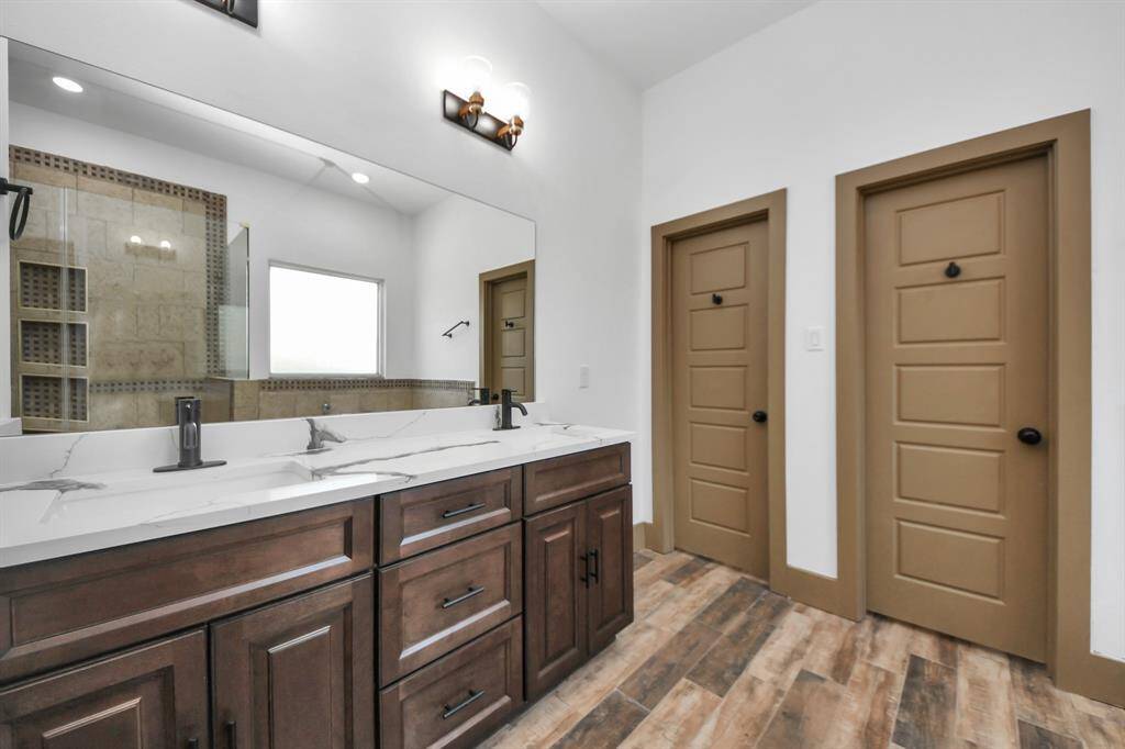 Primary bathroom features a modern design with a double vanity, sleek dark wood cabinets, and contemporary fixtures. It has a large mirror, stylish lighting