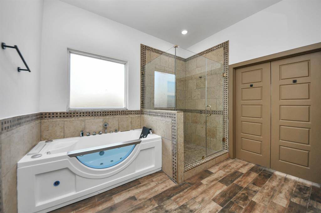 Primary bathroom features a large jacuzzi tub, a spacious glass-enclosed shower, dual sinks with stylish fixtures