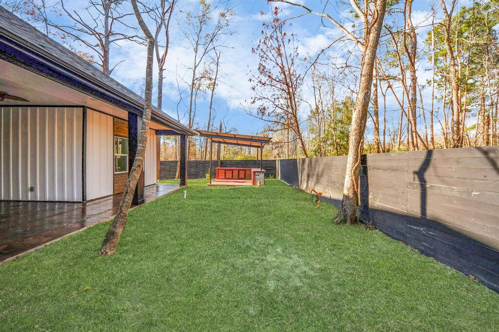 a covered patio area attached to the house, and a wooden privacy fence. There's a cozy seating area under a pergola, ideal for outdoor relaxation and entertaining.