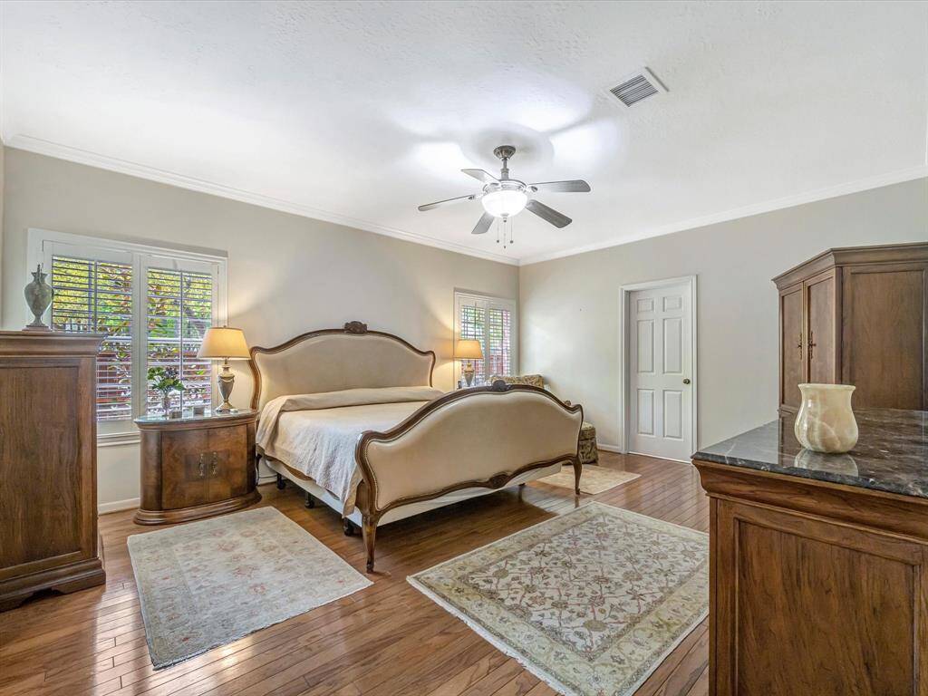 Large primary bedroom with beautiful wood floors and shutters