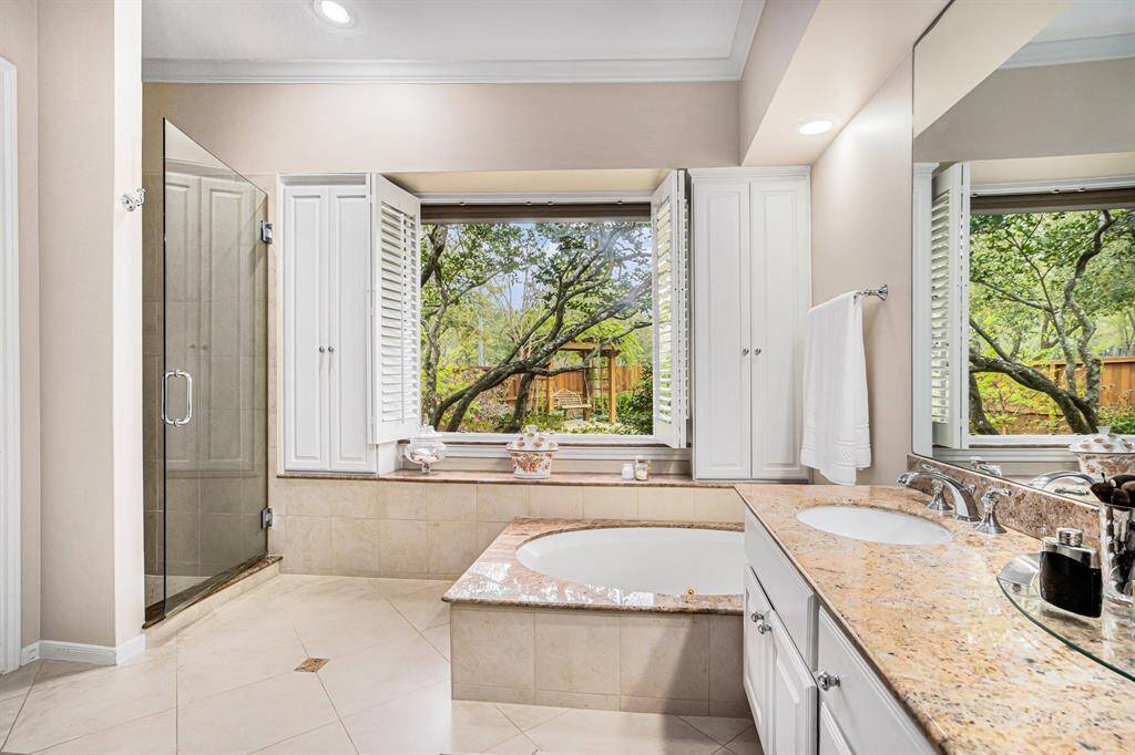 Remodeled primary bath offers jetted tub, double sink vanity with granite countertop, upgraded walk-in shower with jets, 2 walk-in closets, large linen closet. Over looks lush back yard or close shutters for privacy