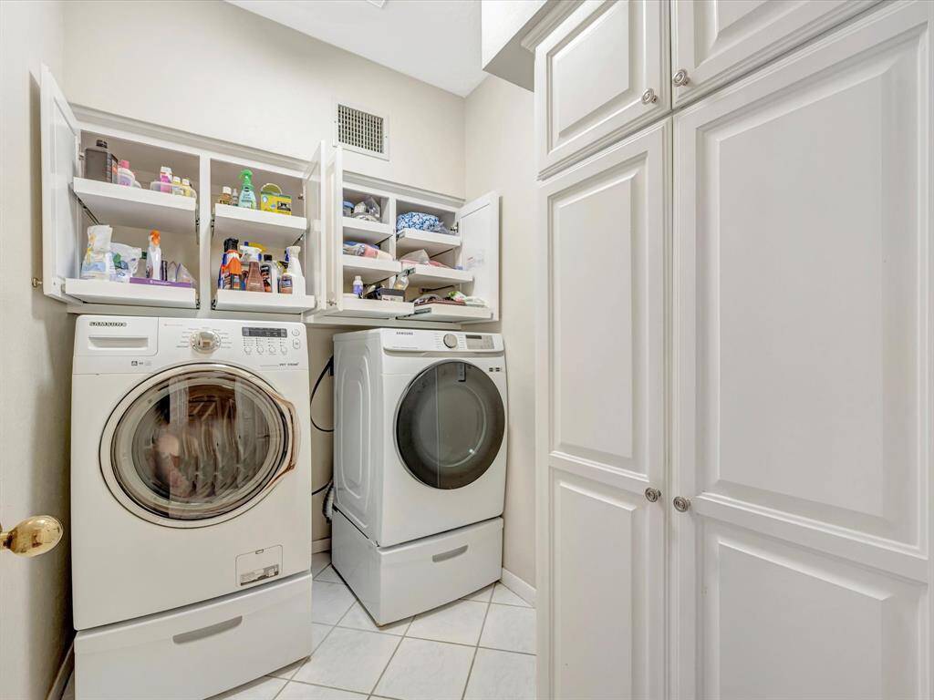 Customized laundry room offers pull out shelves for easier access to your cleaning products, doors to right go to large broom/vacuum closet