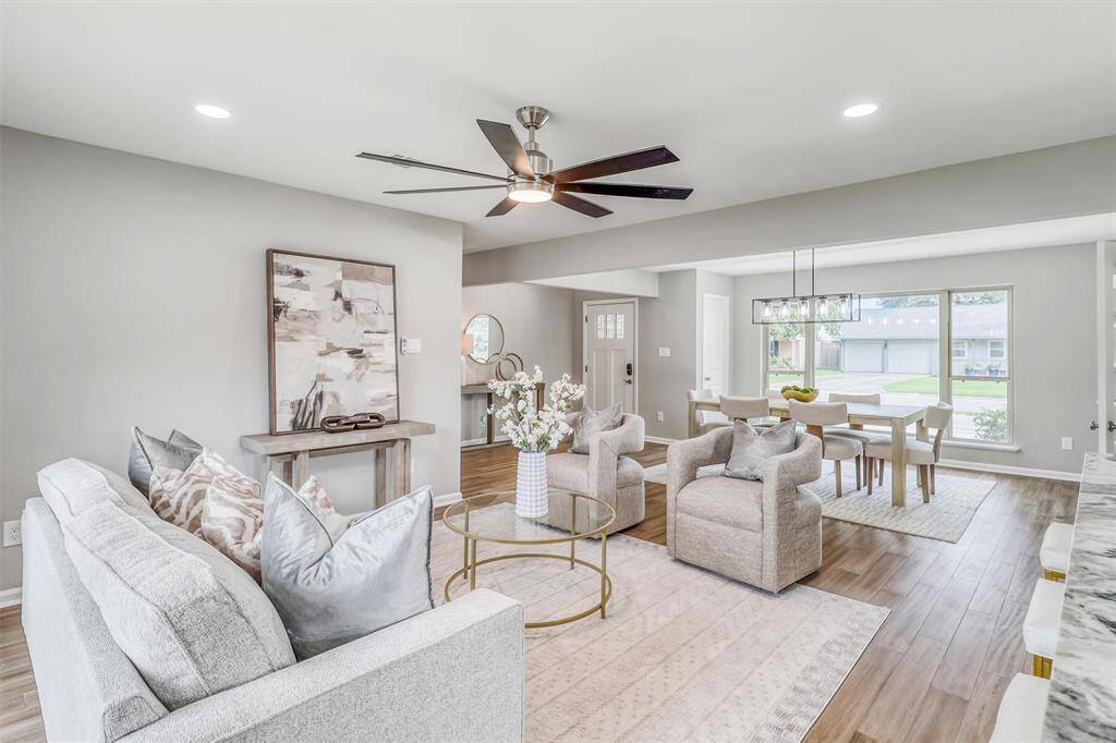 This spacious family room is the perfect place to relax, with soft neutral tones, engineered wood flooring, and abundant natural light pouring in from oversized windows.