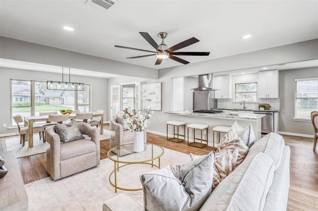 A sleek ceiling fan, recessed lighting, and clear sightlines to the kitchen and dining spaces elevate this room with function and flair.