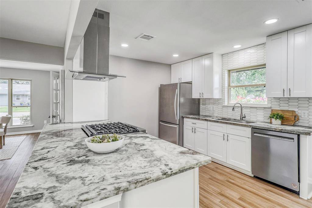 This fully renovated kitchen features crisp white cabinetry, striking granite countertops, and a stunning backsplash that blends modern style with timeless appeal.