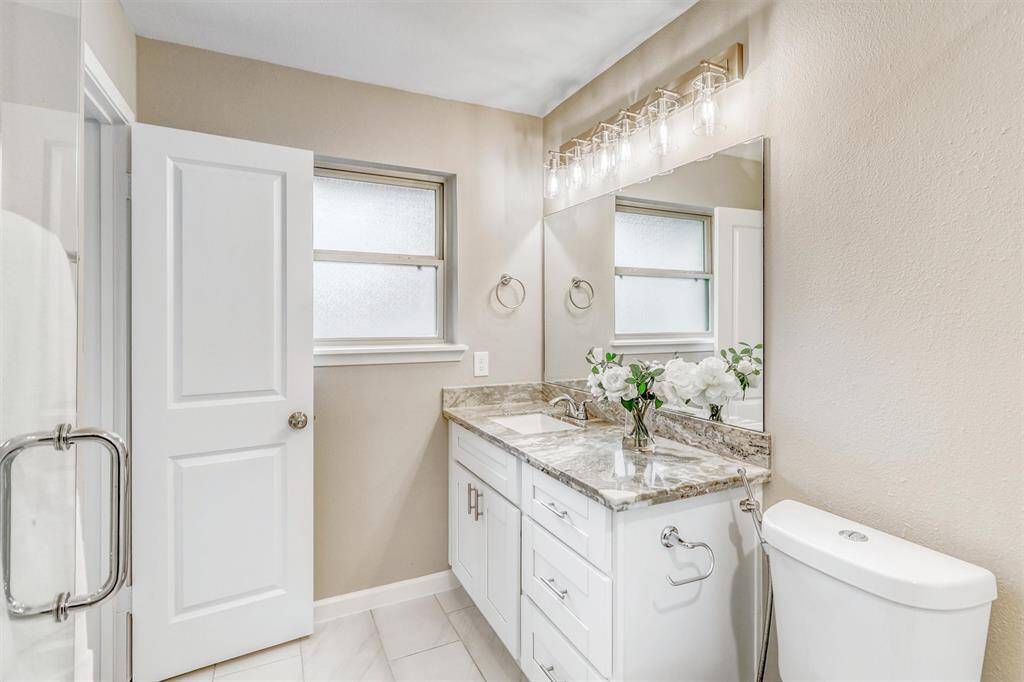 Elegant finishes continue in the bathroom with a large framed mirror, stylish fixtures, and a light, neutral palette.