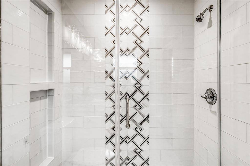 Enjoy a spa-like experience in the fully tiled walk-in shower with built-in niches and a striking accent tile design.
