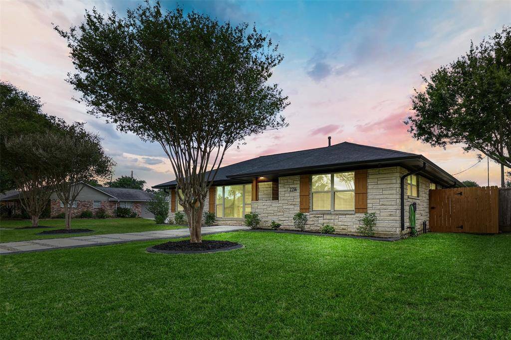 A lush green lawn, mature trees, and thoughtful landscaping frame the glowing exterior of this beautifully updated home, creating stunning curb appeal at twilight.