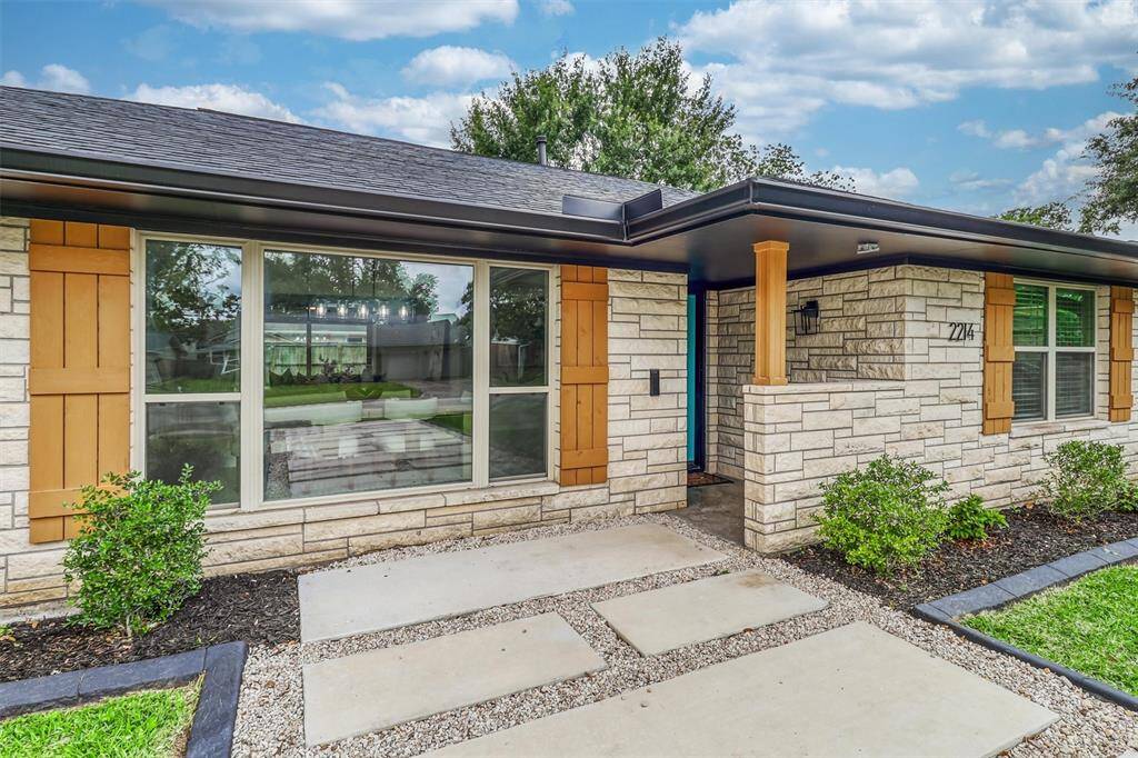 The inviting front entry features a bold blue door, oversized windows, and a covered porch—welcoming you with style and grace.