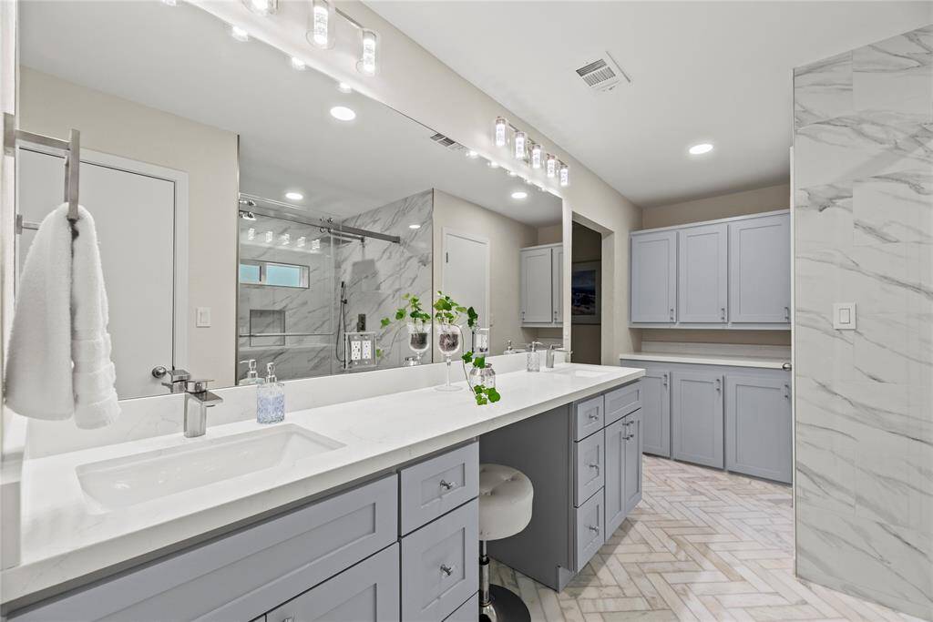 The primary bath features exquisite dual vanities, providing ample personal space along with an abundance of custom cabinetry for seamless organization.
