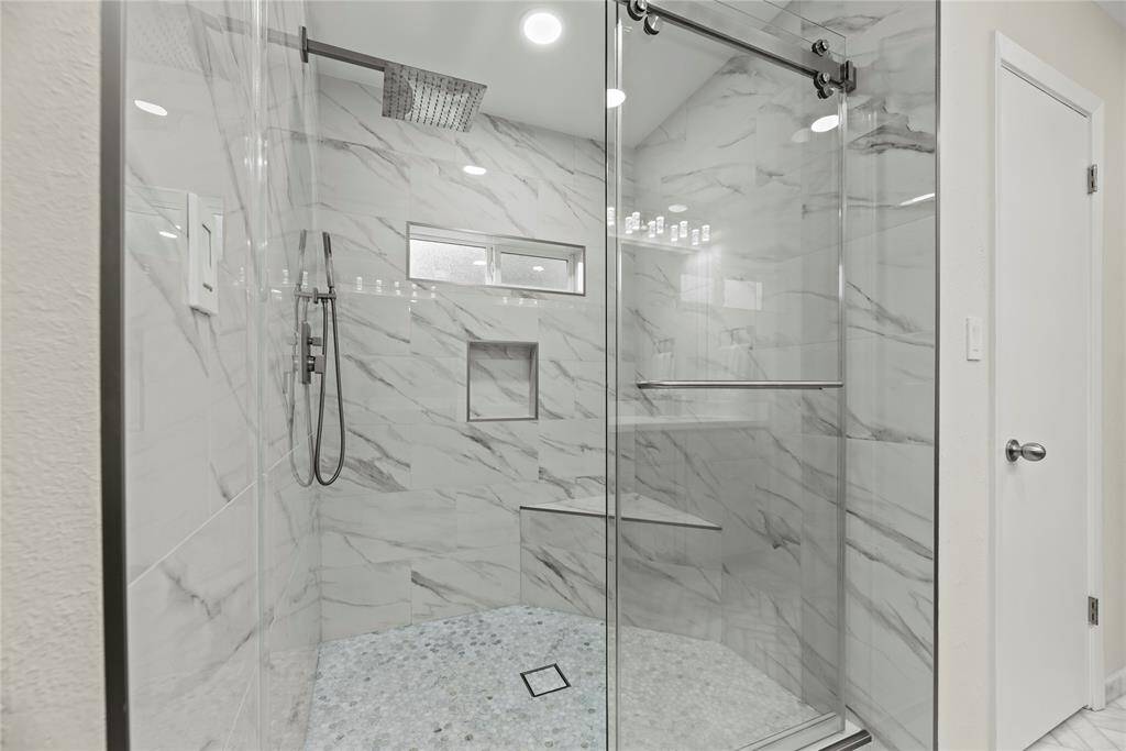 The expansive walk-in shower, adorned with stunning tile work and a sleek glass front, offers a luxurious escape for a quick rinse or a refreshing retreat.