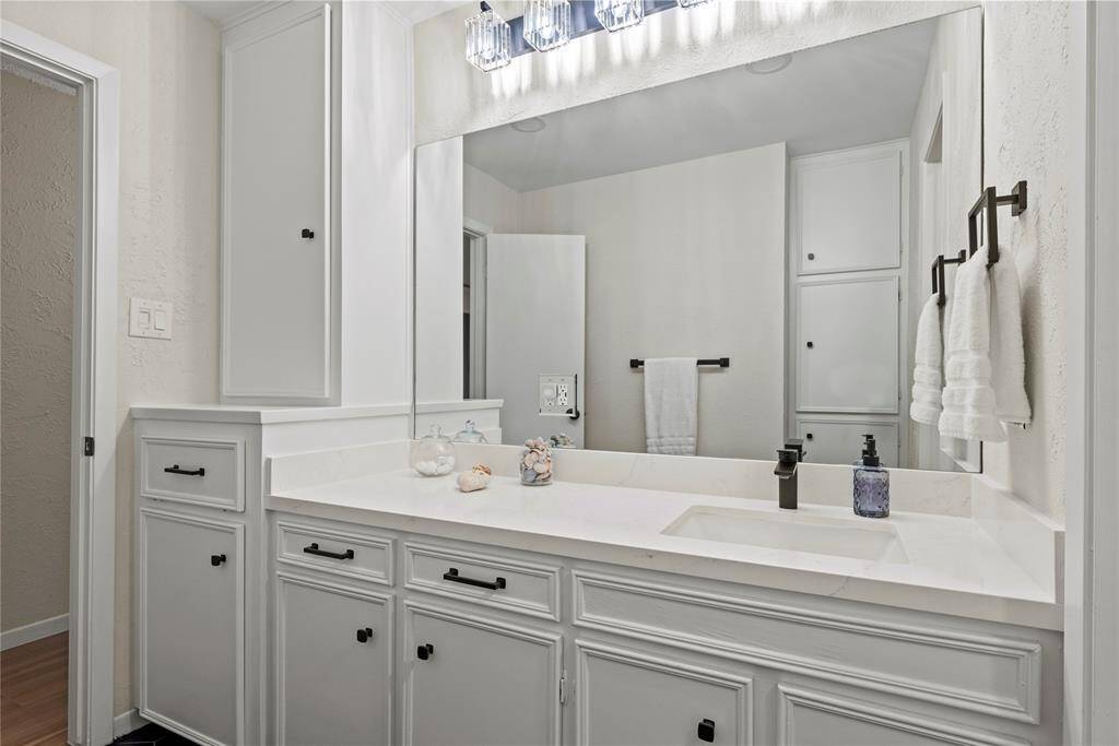 The secondary bath features a spacious vanity, offering ample storage and counter space, making it an ideal setup for family use.
