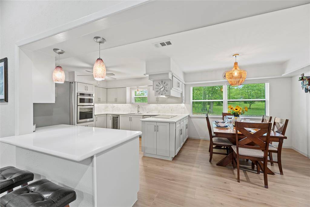 Your chef inspired kitchen awaits! Features include quartz countertops paired with a coordinating backsplash, stainless steel appliances, crisp white cabinets with updated hardware, under cabinet lighting, and an island with breakfast bar seating.