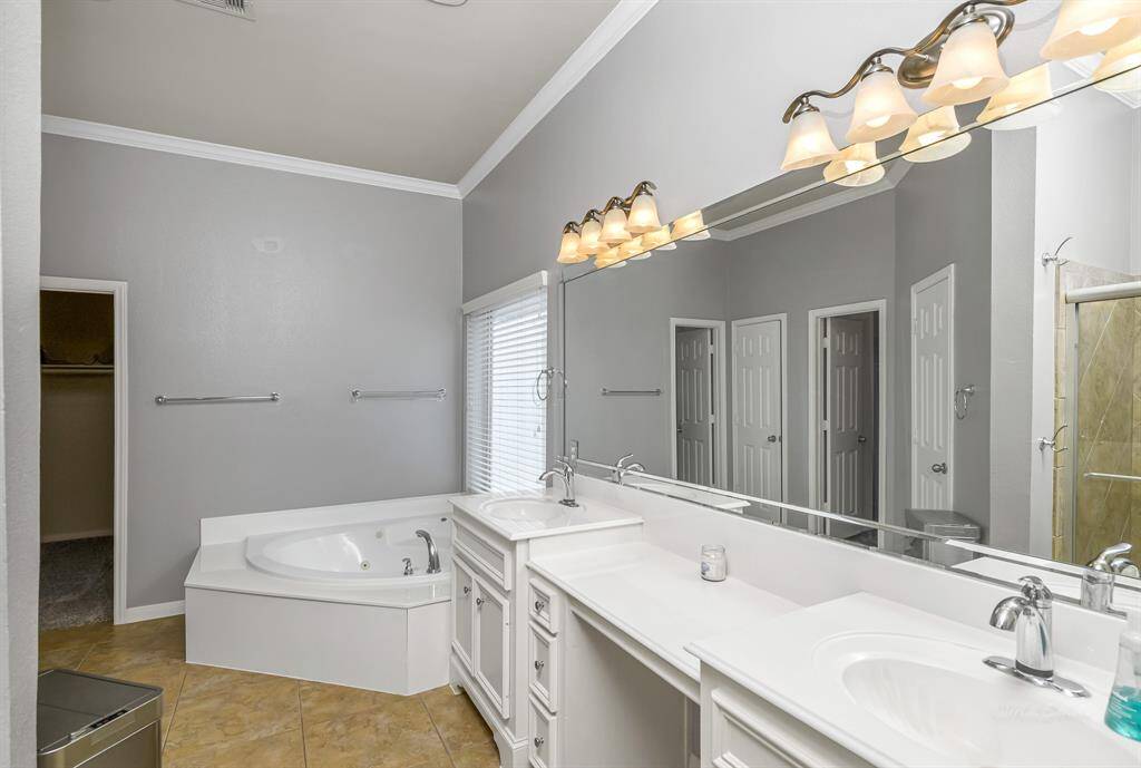 Luxurious primary bath offers dual sinks, vanity, jetted tub, and separate shower