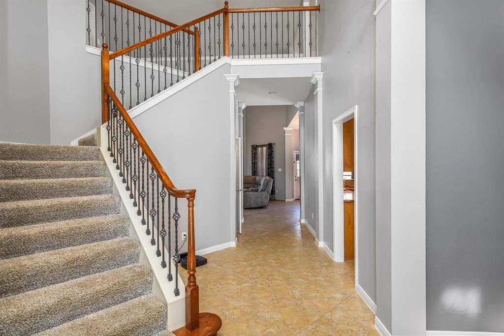 Upon entering the home you are greeted with a high ceilings, tile floors, and this gorgeous staircase featuring wrought iron spindles