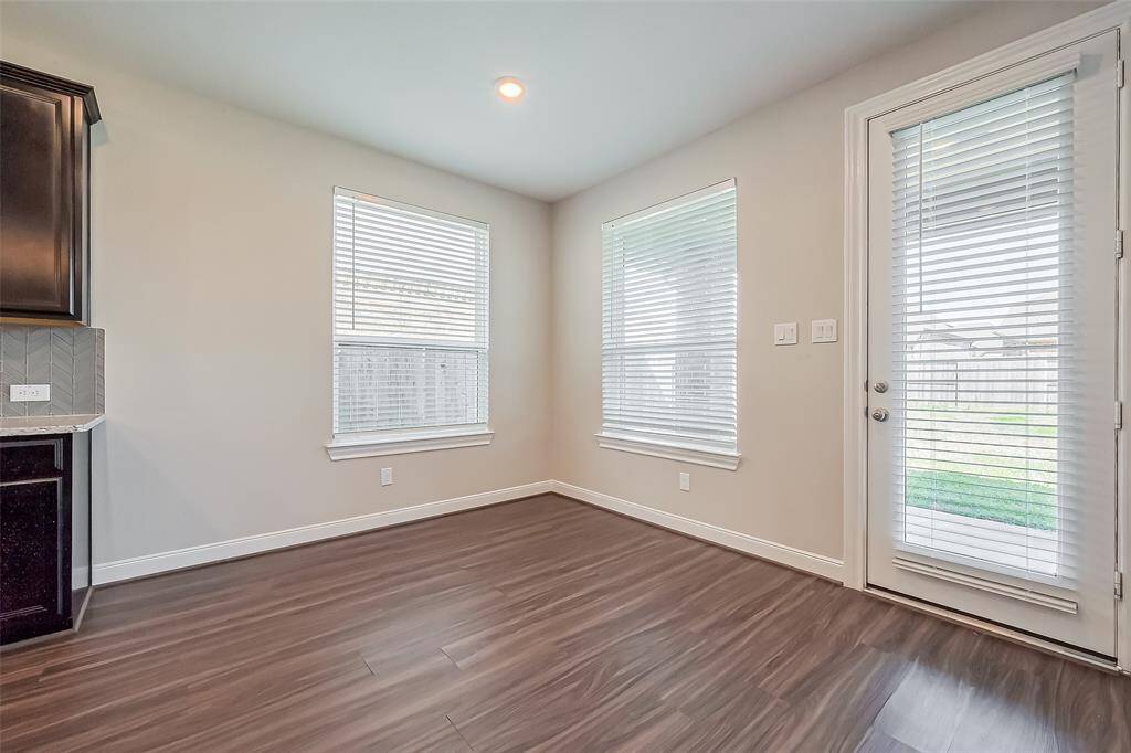 Nestled beside the kitchen, this elegant breakfast area is bathed in natural light from large windows and a glass-paneled door leading outside. The airy ambiance makes it a perfect spot for morning coffee or casual meals.
