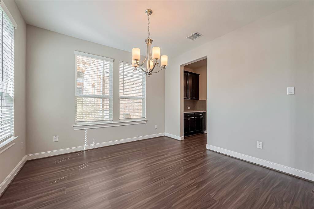 Positioned to the left of the entryway, this generously sized dining space is adorned with multiple windows that usher in soft natural light. An elegant chandelier serves as a centerpiece, and an open doorway provides direct access to the kitchen for effortless entertaining.