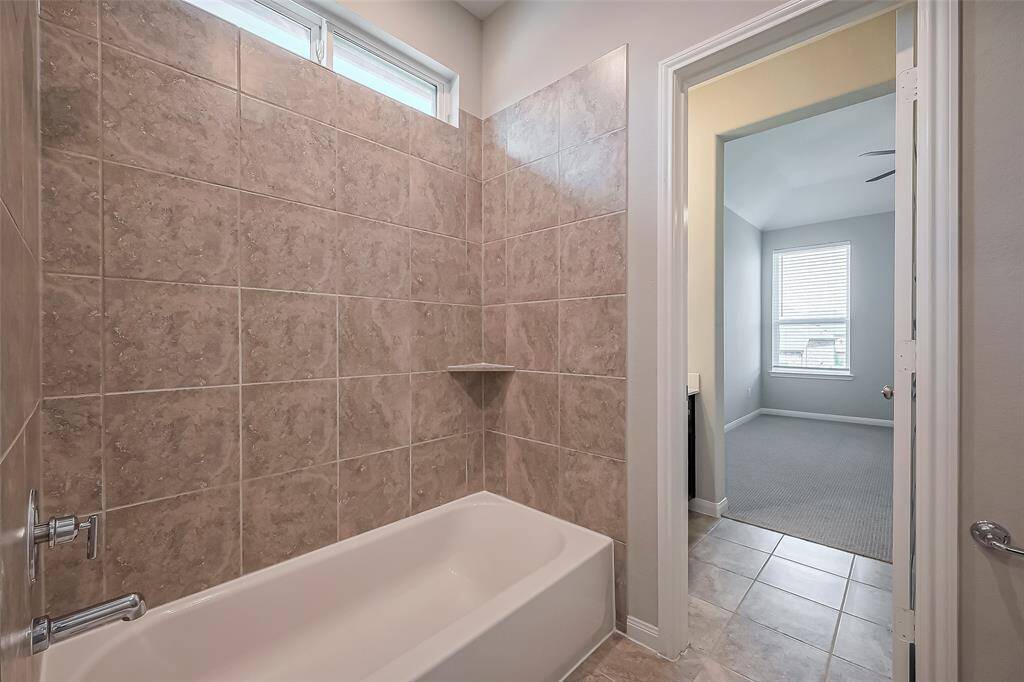 This en suite bath includes a shower-tub combination and a separate vanity area, ensuring functionality and comfort.