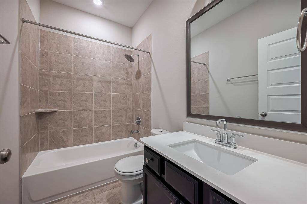 Well-lit and thoughtfully arranged, this full bathroom includes a shower-tub combination and a vanity area with under-storage and a large mirror, balancing style and practicality.