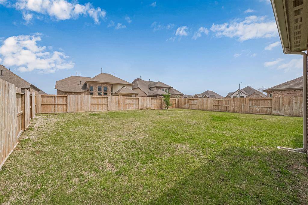 A sprawling expanse of lush green grass stretches across the fenced backyard, offering endless possibilities. Whether for recreation, gardening, or future enhancements, this vast open space provides both privacy and potential.