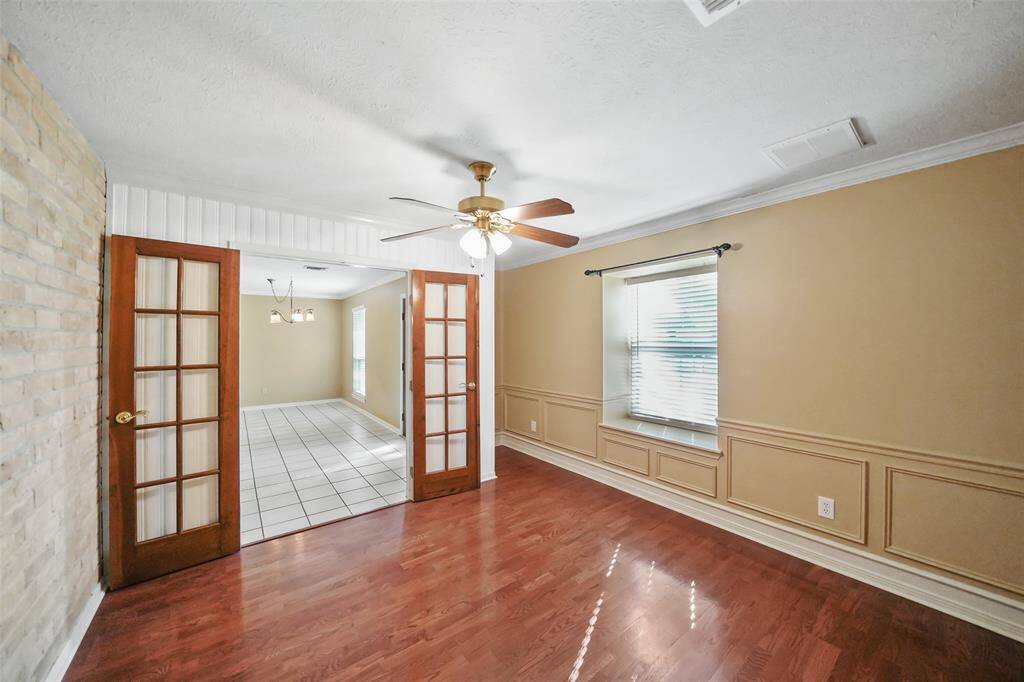 The study features fresh paint, beautiful wood floors, an exposed brick accent wall, and elegant French doors - wonderful for work or relaxation.