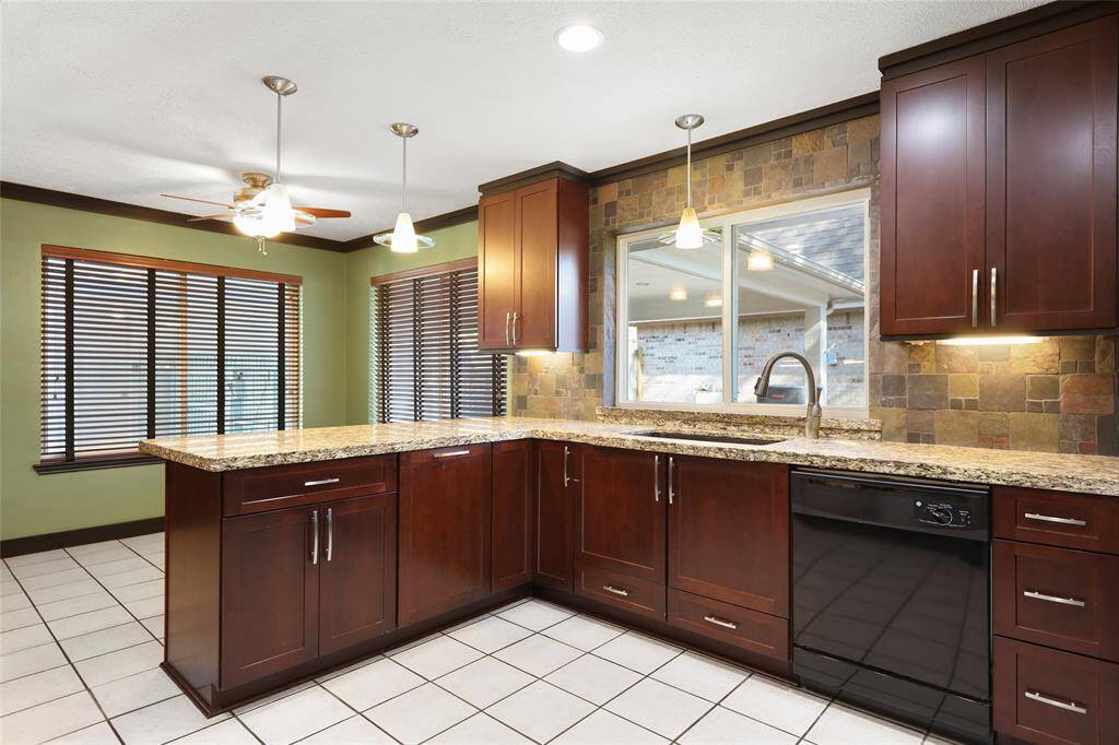 Stylish kitchen features include elegant granite countertops, a spacious sink, a pull-out trash cabinet and modern pendant lighting.