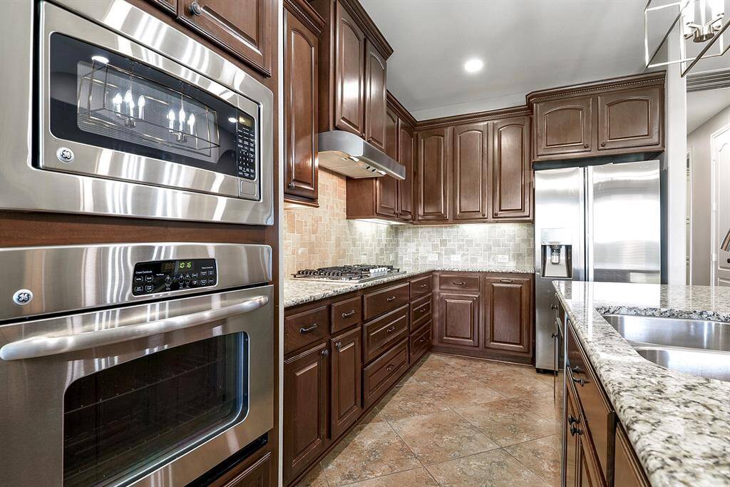The spacious kitchen features matching stainless steel appliances, including a wall oven and microwave, along with a five-burner gas stove. All cabinetry is equipped with elegant hardware, enhancing both the functionality and style of the space.