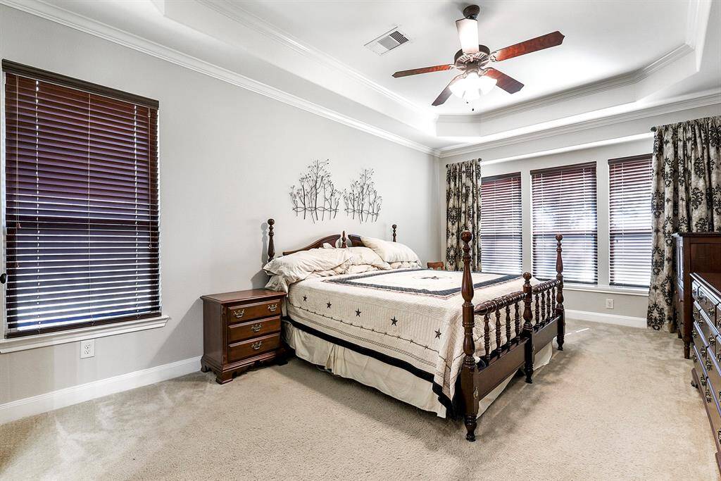 Tucked in the corner of the home, the primary en suite is conveniently located on the main floor, featuring a wall of windows that overlook the backyard, filling the room with natural light and offering a serene view.