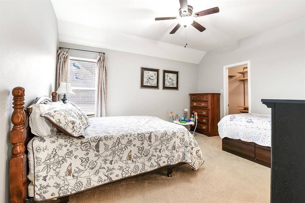 The upstairs bedroom features a walk-in closet, high ceilings with a ceiling fan, and ample space to comfortably accommodate two large beds along with additional furniture—a perfect setup for guests, shared rooms, or multi-use functionality.