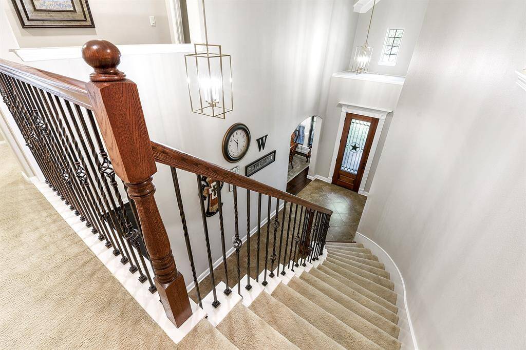 From upstairs, you can look down over the elegant curved staircase and the two-story foyer, with a direct view of the front door, creating a grand and open feel when entering the home.
