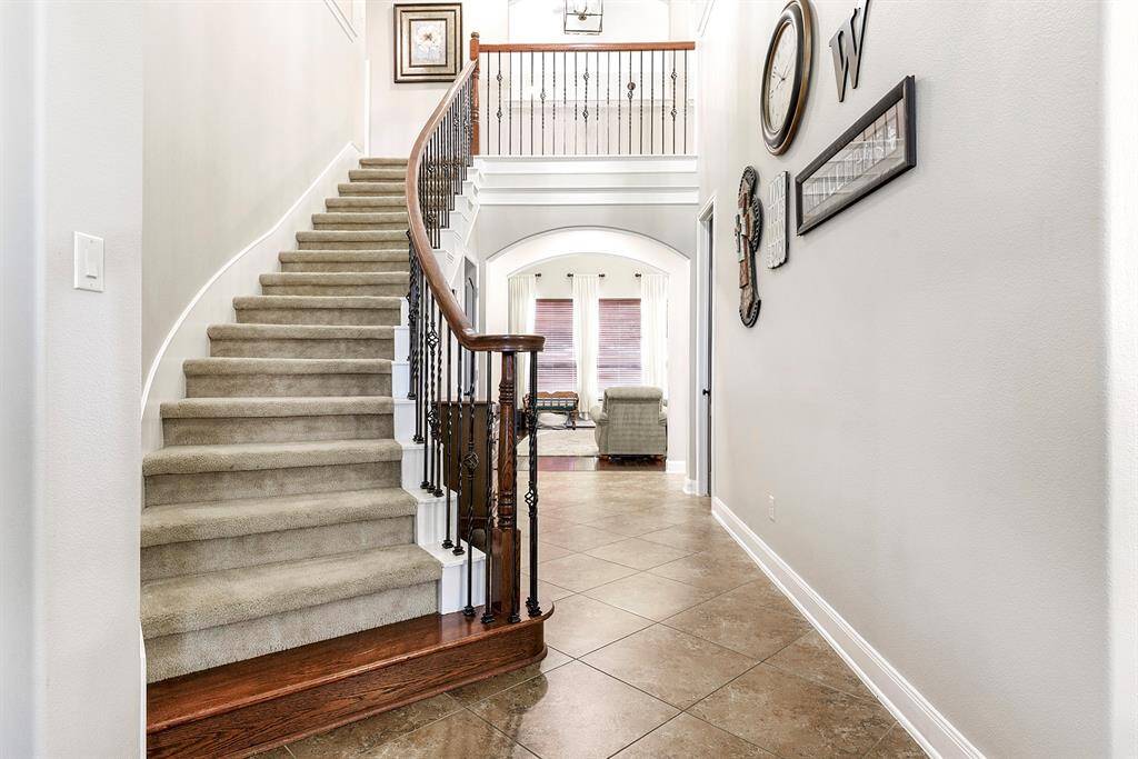 As you enter the grand foyer, you’re welcomed by a stunning two-story entryway and an elegant curved staircase that leads to the second floor. To your left, French doors open into a private home office, perfect for working from home or managing daily tasks in a quiet space.