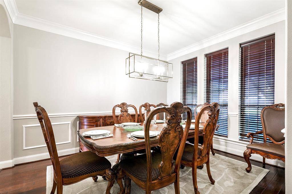 Across from the home office is an elegant formal dining room with front yard views, featuring the same beautiful hardwood flooring and crown molding for a cohesive look. This room is generously sized, offering plenty of space for a large dining set—perfect for hosting family gatherings or formal dinners. The formal dining room offers dual access, including a convenient pass-through into the kitchen.