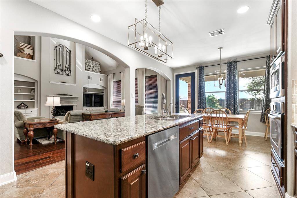 From the formal dining room, you enter the open-concept kitchen, featuring a large island with a sink that faces out toward the breakfast area and spacious living room. This open layout allows for seamless interaction while entertaining and offers clear views into the backyard, bringing in plenty of natural light.
