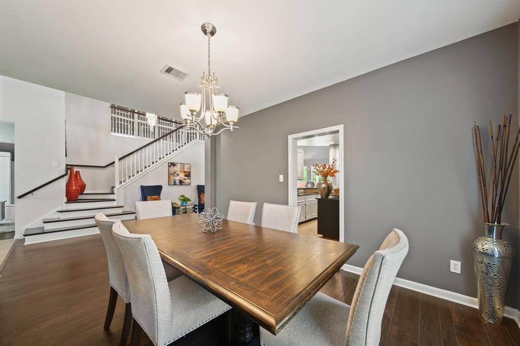 This elegant dining room features rich wood flooring, designer gray paint, and a chic chandelier that sets the tone for everything from festive holiday dinners to casual family meals.