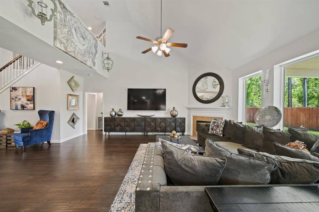 A view of the upstairs balcony, stylish lighting, and seamless flow into the other living areas highlight the thoughtful design and spacious layout of this beautiful family room.