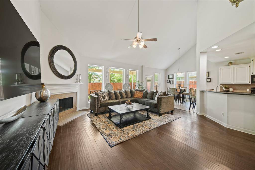 This spacious family room is anchored by a cozy corner fireplace and flooded with natural light from a wall of windows overlooking the backyard.