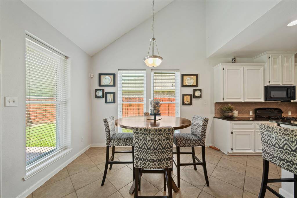Located just off the kitchen, the breakfast area features neutral tile flooring, soft paint tones, and a stylish light fixture overhead.