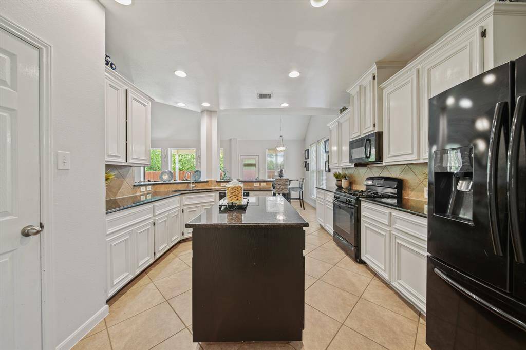 A dark-stained center island adds contrast and extra prep space, while the surrounding layout provides ample storage and workspace for the home chef.